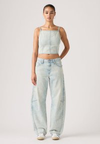 Ανοιχτό μπλε denim κοντό τοπ με τετράγωνο ντεκολτέ, συνδυασμένο με άνετο ανοιχτό μπλε τζιν παντελόνι. Διαθέτει διακριτική ξεθώριαση και κλασικό σχεδιασμό με πέντε τσέπες.