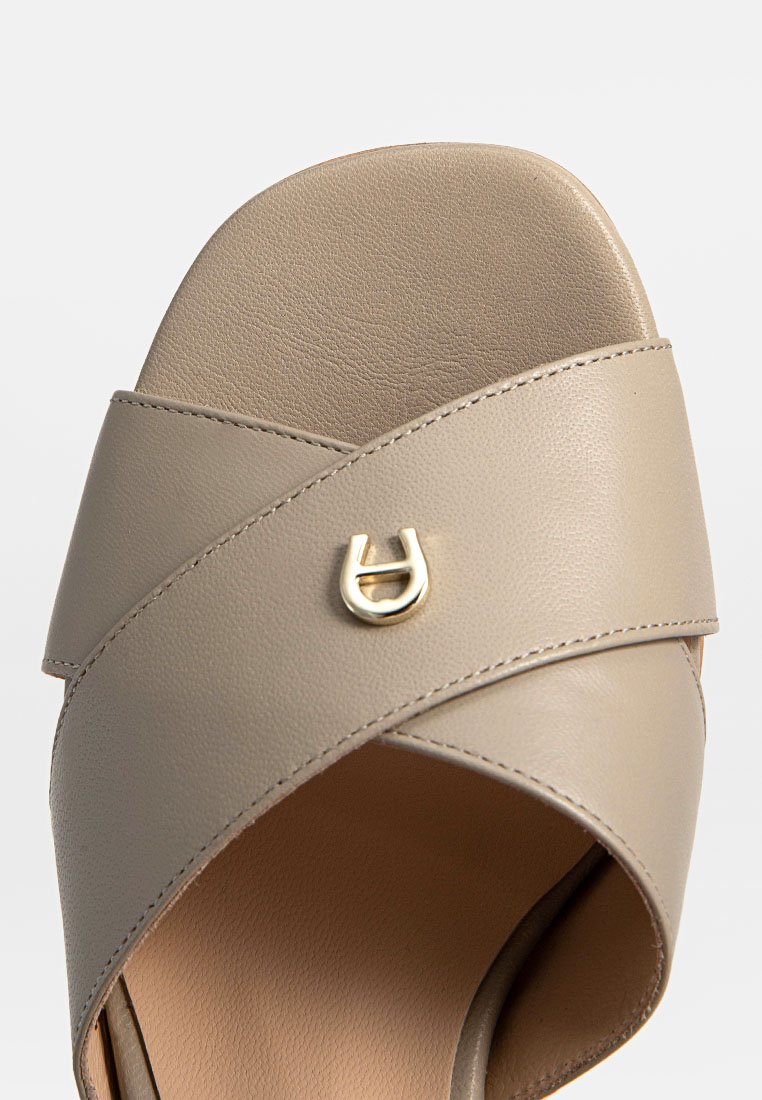 Beige Leder-Sandale mit gekreuzten Riemen und einer kleinen goldenen dekorativen Schnalle auf dem vorderen Riemen.