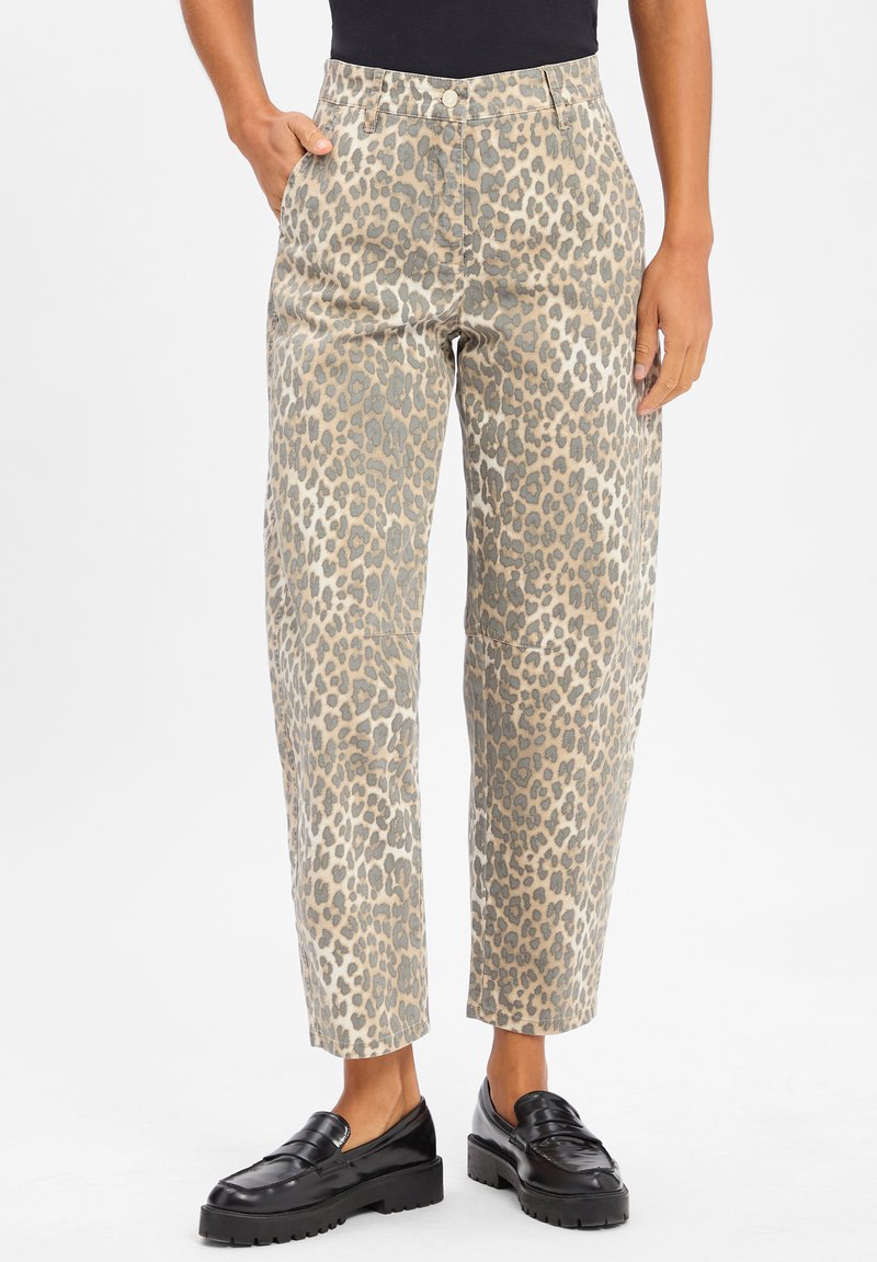 Luipaardprint broeken in beige en grijs, high-waisted, met zijzakken en een relaxte fit, gecombineerd met chique zwarte loafers.