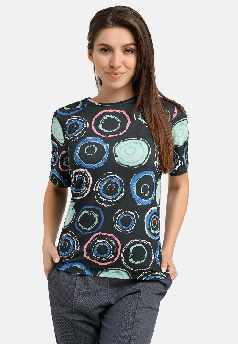 Black short-sleeve shirt featuring colorful circular patterns in shades of blue, green, and pink. Made from soft, lightweight fabric.