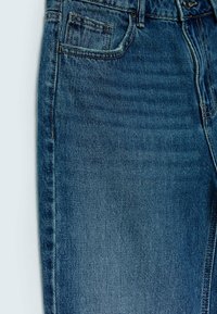 Jeans de denim en un color azul intenso, con un bolsillo frontal, detalles de costura sutiles y una tela texturizada con un corte clásico.