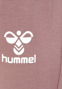 Fioletowy materiał z białym logo "hummel" i stylizowanym wzorem pszczoły, posiadającym symetryczne skrzydła i wzorzyste ciało.
