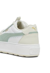 Sněrovací obuv Puma s bílou koženou svrškem a světle zelenými akcenty, texturovaným potahem, polstrovaným límcem a silnou bílou podrážkou. Viditelné zlaté branding.