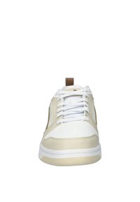 Sneaker beige e bianco con linguetta imbottita, texture perforata sulla punta e dettagli in marrone sui lati. Chiusura con lacci standard.