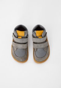 Pantofi gri din suede și plasă, cu două curele Velcro, tălpi din cauciuc și accente galbene la călcâi și pe limbă. Vedere din partea de sus.