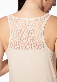 Beiges Tanktop mit einem floralen Spitzenrücken, rundem Ausschnitt und dünnen Trägern. Glatter Stoff mit einem strukturierten Spitzen-Detail.