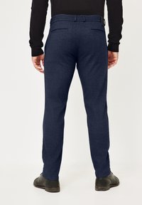 Marineblaue Hosen aus strukturiertem Stoff, mit geradem Schnitt, Gürtelschlaufen, zwei Gesäßtaschen und kombiniert mit schwarzen Schuhen.