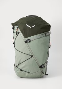 Ryggsekk med mørkegrønn topp og lysegrønn kropp, med en slank form, justerbare stropper, bungee-snorer og detaljer med merkevarelogo.