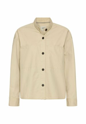 Beżowa koszula na guziki z długimi rękawami, stójką i pięcioma widocznymi ciemnymi guzikami z przodu.