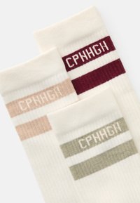 Tre vita ribbade strumpor med färgade ränder och texten "CPNHGH" i beige, vinröd och olivgrön vid toppen.