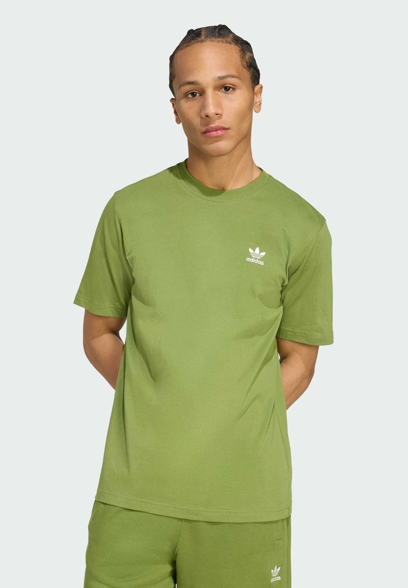 Zelené bavlnené tričko s okrúhlym výstrihom, krátkymi rukávmi a bielym logom Adidas na hrudi, doplnené o zodpovedajúce šortky.