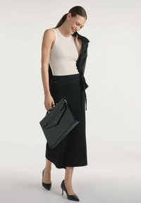 Czarna spódnica ołówkowa, biała podkoszulka w prążki i czarna skórzana kurtka. Nosi teksturowaną czarną torebkę. Czarne szpilki o spiczastym nosku. Prosty, elegancki fason.