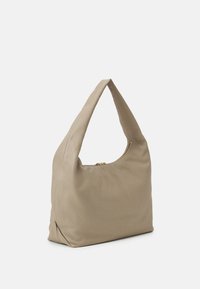 Beige läderaxelväska med ett krökt handtag och dragkedjestängning. Slät textur och minimalistisk design, med en mjuk och slapp form.