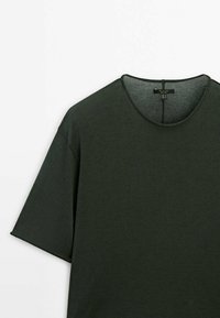 Mørkegrøn kortærmet T-shirt med rund hals og synlig mærkeetiket inden i kraven på hvid baggrund.