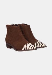 Botines de ante marrón con una puntera de patrón de cebra, que cuentan con una cremallera lateral y un bajo tacón de madera.