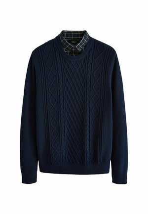 Navy blue knitted sweater with cable knit patterns, round neckline, and long sleeves. Underlayer features a checkered pattern in dark tones.