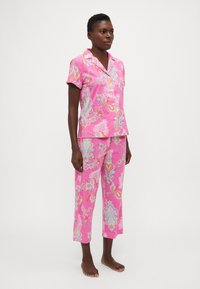 Rozā pidžamu komplekts, kas sastāv no īsām piedurknēm ar pogu topu un potītes garuma biksēm, dekorēts ar krāsainu paisley rakstu. Izgatavots no viegla auduma.