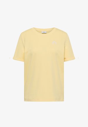 Vaaleankeltainen lyhythihainen T-paita pyöreällä pääntiellä, vasemmassa rinnassa pieni valkoinen logo ja käännetyt hihansuut.