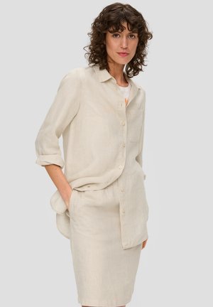 Beige Leinen-Hemdkleid mit aufgerollten Ärmeln, kombiniert mit einem passenden knielangen Rock. Hat eine einzelne Brusttasche.