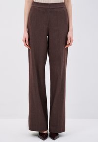 Bruine wijde broek met een rechte snit, textuurstof en een subtiel visgraatpatroon. Heeft een standaard tailleband en geen zichtbare bevestigingsmiddelen.