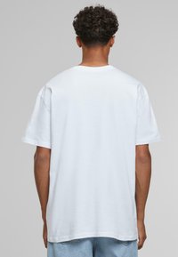 Hvid kortærmet t-shirt med rund udskæring, afslappet pasform og glat bomuldsstruktur, set bagfra.
