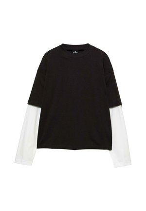 Zwarte T-shirt met korte mouwen, gelaagd over een witte blouse met lange mouwen, met een ronde hals en een losse pasvorm. Zachte stoffen textuur.