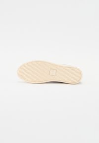 Sneaker sole in rubber with a beige color and textured grip pattern. Features a square logo in the center.