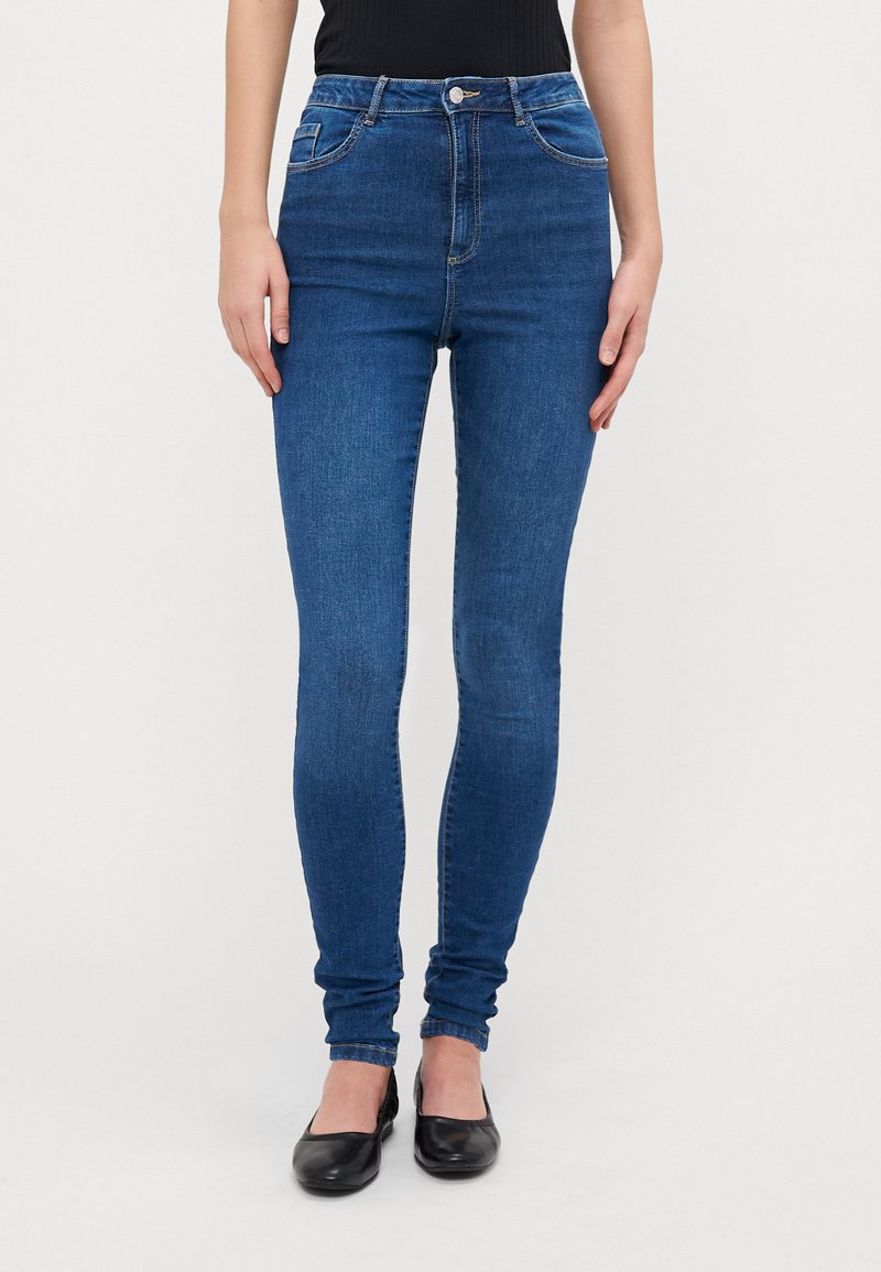 Skinny denim jeans in dark blue with a smooth texture, high waist, five-pocket design, and a button closure. Accented with subtle stitching.