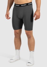 Grå atletisk shorts med en tætsiddende pasform, der har en sort elastik med teksten "SMILODOX". Stofletningen har en glat, struktureret overflade.