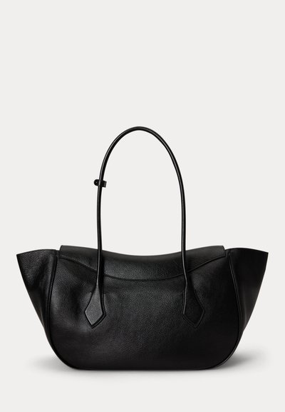 Bolso de mano negro de cuero con asas largas y delgadas y una forma curva, ligeramente irregular, sobre un fondo blanco liso.