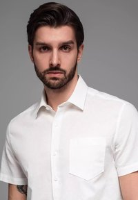 Witte short-sleeve shirt gemaakt van een gladde stof, met een standaard kraag en een enkele borstzak met een licht gestructureerde afwerking.