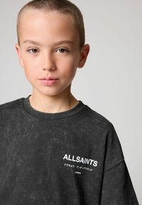 Černé tričko s krátkým rukávem a texturovaným povrchem. Na přední straně se nachází bílé logo "ALLSAINTS" a japonský text. Kulatý výstřih.