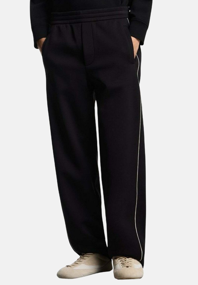 Zwarte sweatpants met een relaxte pasvorm, voorzien van witte zijpiping en een elastische tailleband met trekkoord. Gemaakt van zachte stof met een gladde textuur.