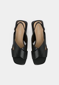 Μαύρα δερμάτινα σανδάλια με σταυρωτό λουράκι, τετράγωνες μύτες και ρυθμιζόμενες αγκράφες στο πλάι, με μπεζ εσωτερικές σόλες με την επωνυμία "Anna Field".