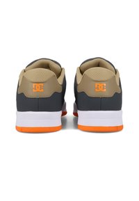 Sneakers DC w ciemnoszarym i beżowym wierzchem, pomarańczowymi akcentami, białą podeszwą środkową, siateczkową podszewką i wyściełanym kołnierzem dla większego komfortu.