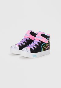 Svarte høyde sneakers med en rosa og blå stropp, lilla snøring og en naglet tåhette. Regnbue hjerte-design på siden.
