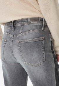 Graue Denim-Jeans mit hoher Taille, dezentem Used-Look und minimalistischer Naht. Mit zwei Gesäßtaschen und einem Logo-Tag.