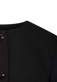 Sort plagg med rund halslinning og to blanke svarte knapper med gullfargede kanter langs frontlukking.