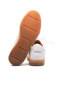 Sneakers bianchi in pelle con suola in gomma testurizzata, caratterizzati da un accento beige. La parte posteriore presenta un design cucito e un'impressione del logo.