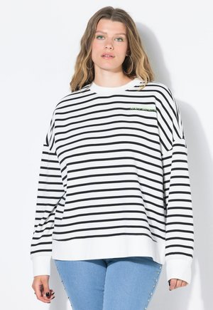 Gestreepte sweatshirt in wit en zwart met lange mouwen, voorzien van een ronde hals en een klein groen logo accent op de borst. Gecombineerd met blauwe jeans.
