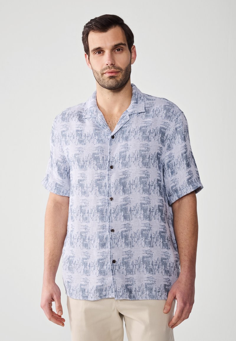 Camisa de botones de manga corta en azul claro y blanco con un patrón abstracto texturizado; presenta un cuello clásico y botones oscuros.