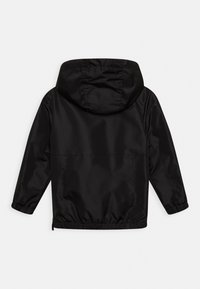 Zwarte waterdichte jas met een capuchon, voorzien van elastische manchetten en een gerimpelde zoom. Glad textuur met een minimalistisch ontwerp, zonder zichtbare logo's.