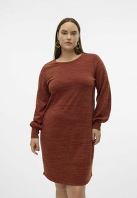 Abito a maniche lunghe di colore ruggine realizzato in un morbido tessuto testurizzato. Presenta un collo rotondo e maniche ampie con polsini arricciati.