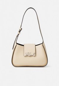 Beige leather handbag with a structured shape, black trim, adjustable strap, and a silver logo accent on the front flap.