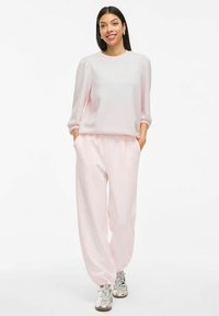 Set di abbigliamento da casa rosa chiaro composto da un pullover morbido a maniche lunghe e pantaloni con vita elasticizzata, abbinato a sneakers argentate lucide.