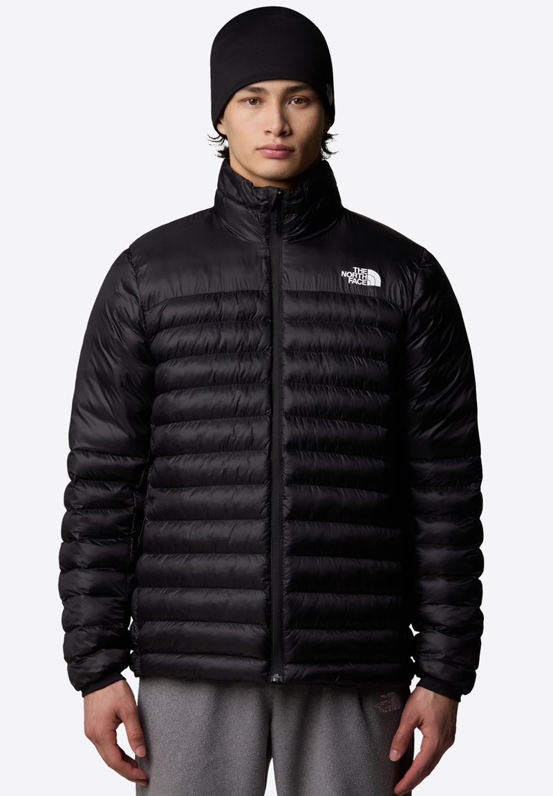 Črna puhovka z vodoravno prešitim vzorcem, sprednjim zadrgo, visokim ovratnikom in logotipom The North Face na levem prsnem delu.