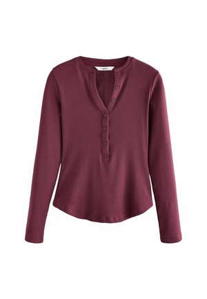 Maglietta a maniche lunghe color bordeaux con scollo rotondo, dotata di apertura con bottoni e texture a coste. L'orlo è leggermente curvato nella parte inferiore.