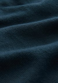 Tejido de ribete azul marino con textura visible, que presenta líneas suaves y dobladas que crean un patrón ondulado. El material parece ligeramente difuso.