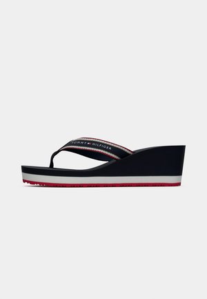 Platformowe klapki w odcieniu granatowym z gumową podeszwą, białą wkładką i czerwonymi akcentami. Posiadają materiałowy pasek z logo "TOMMY HILFIGER".