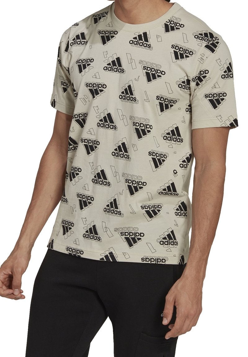 Vale beige T-paita, jossa on mustat painetut Adidas-logot ja geometriset muodot. Valmistettu pehmeästä kankaasta, jossa on klassinen pyöreä kaula-aukko ja lyhyet hihat.